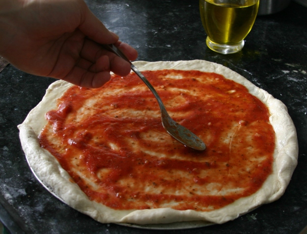 פיצה ביתית: מורחים את הרוטב בעזרת החלק החיצוני של הכף